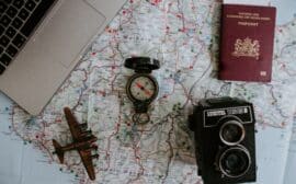 Avion miniature, boussole, passeport et appareil photo sur une carte du monde