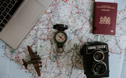 Avion miniature, boussole, passeport et appareil photo sur une carte du monde