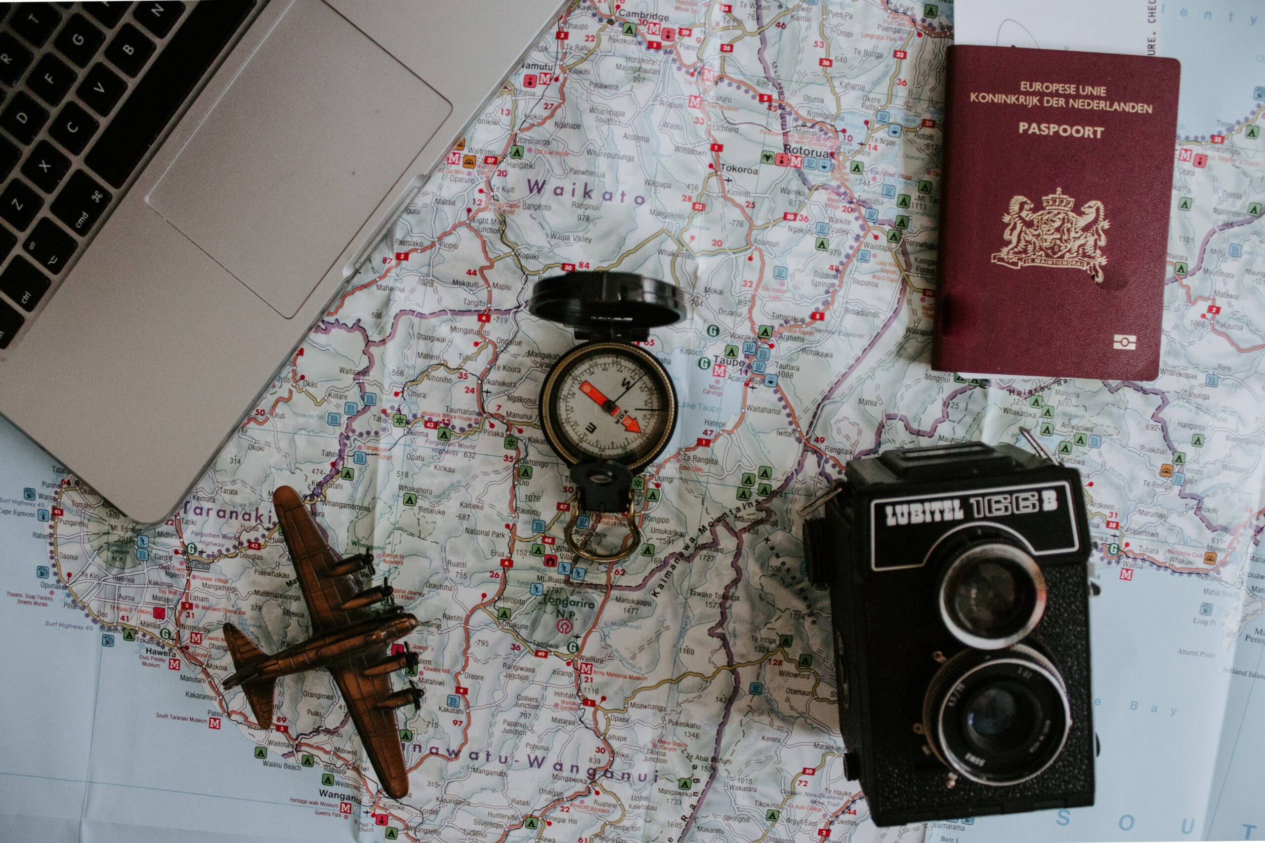 Avion miniature, boussole, passeport et appareil photo sur une carte du monde