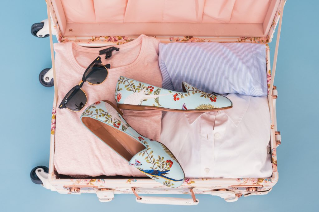 Valise rose sur fond bleu pastel