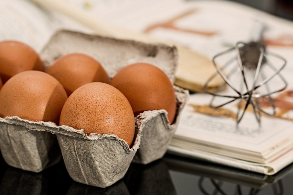 boîte d'oeufs et fouet posés sur une table